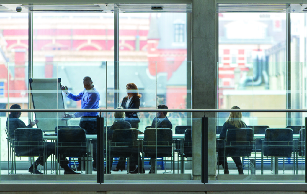 Office employees sitting at a conference table discussing pros and cons